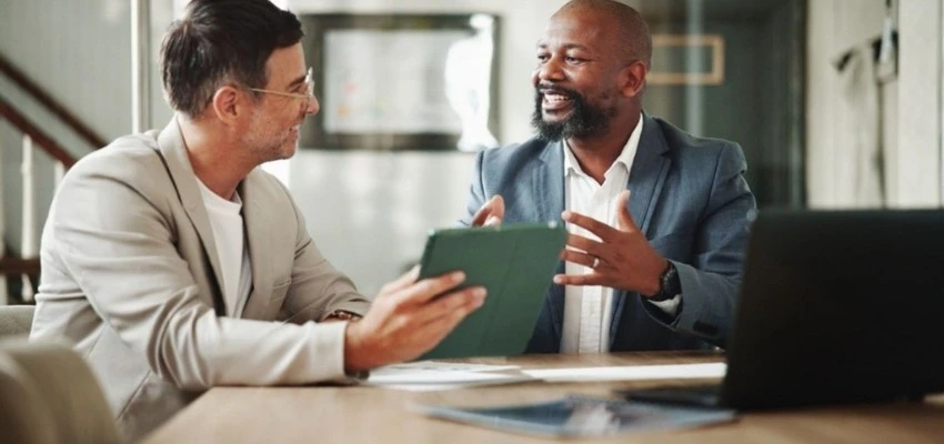 Business professionals reviewing documents during ISO certification audit preparation meeting in UAE office