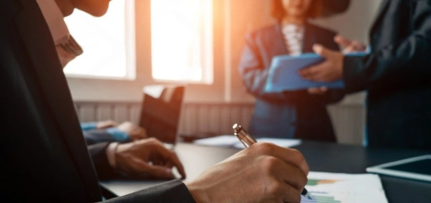 Team reviewing audit documents during ISO certification process evaluation meeting in professional office setting